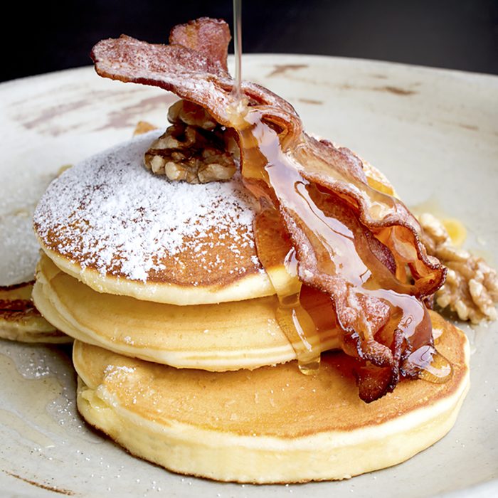 Stack of delicious pancakes with bacon, honey, nuts and caramelize banana; Shutterstock ID 384717481