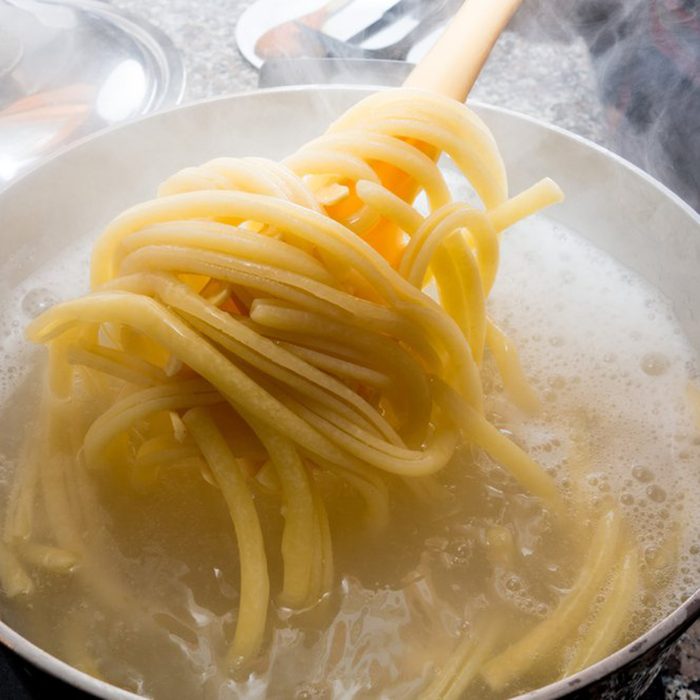 Cooked pasta being pulled from boiling water