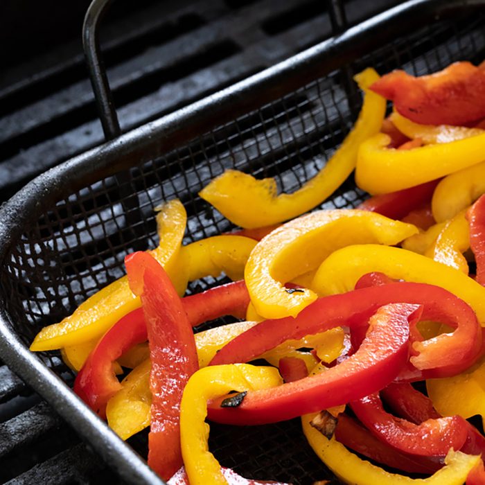 Close up on raw yellow and red bell peppers for fajitas, in a barbecue grill basket