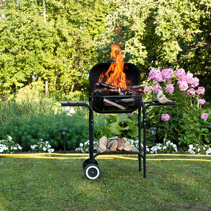 grilling safety Flames burning in a barbecue standing in a pretty garden as the coals are prepared for grilling an array of meat for a lunchtime cookout;