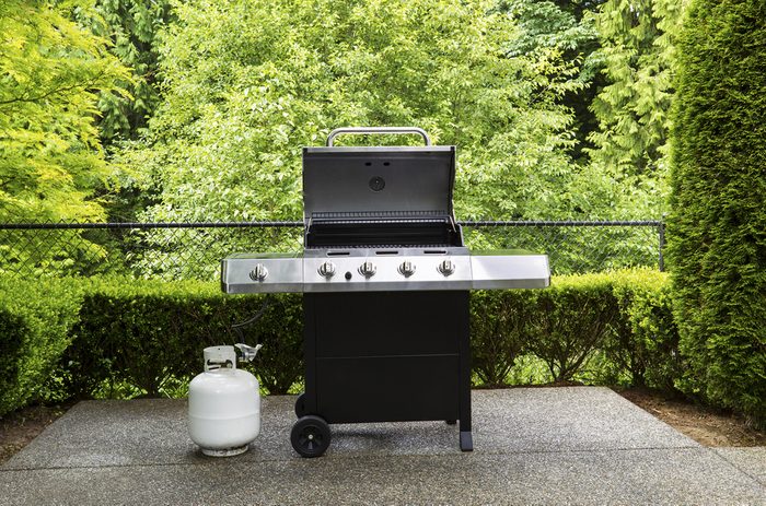 Horizontal photo of large barbeque cooker, with lid up, on concrete outdoor patio with woods background ; Shutterstock ID 144992224; Job (TFH, TOH, RD, BNB, CWM, CM): TOH How to Burp a Propane Tank