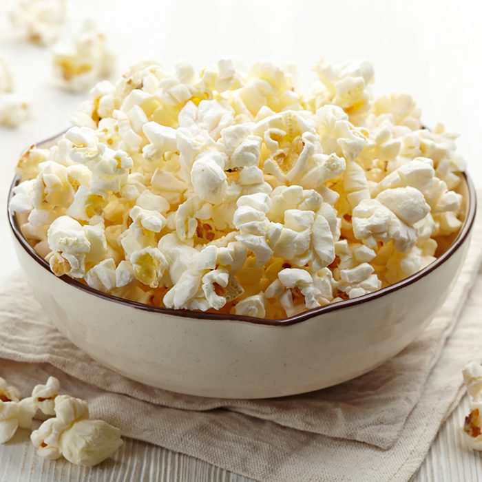 Bowl of fresh popcorn on white wooden background