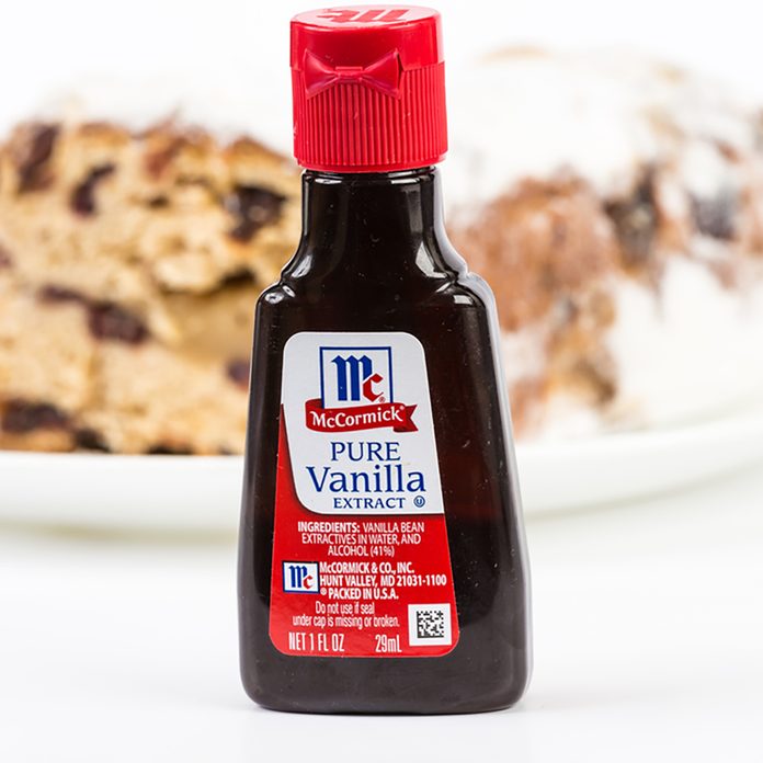 Small bottle of McCormick Pure Vanilla Extract with baked cake in background. Horizontal with copy space.