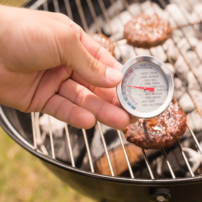 grilling safety Man using meat thermometer while barbecuing on a sunny day