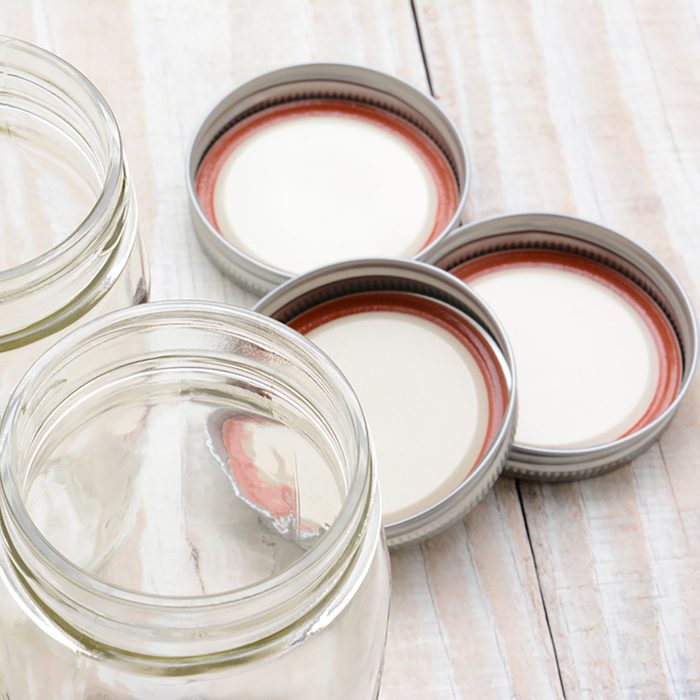 Closeup of three glass canning jars on a rustic wood farmhouse style kitchen table. 