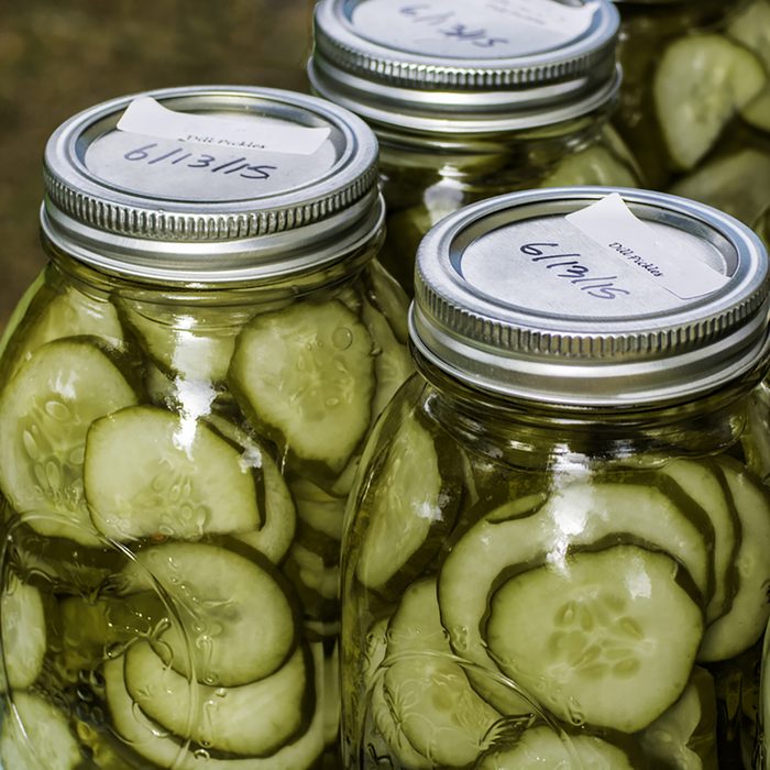 Homemade dill pickles canned in glass jars on display at a farmer's market.