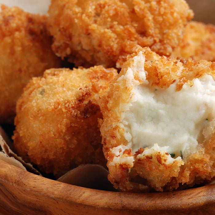 Potato croquettes (mashed potatoes seasoned with fresh chives; breaded and deep fried). Macro with shallow dof. Selective focus on opened croquette