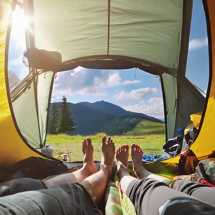 Two people lying in tent with a view of mountains.
