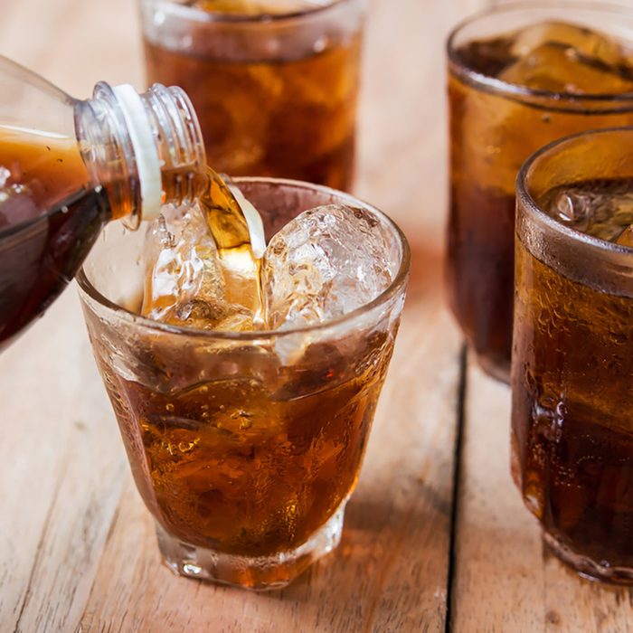 Cola drink is poured into a glass with ice