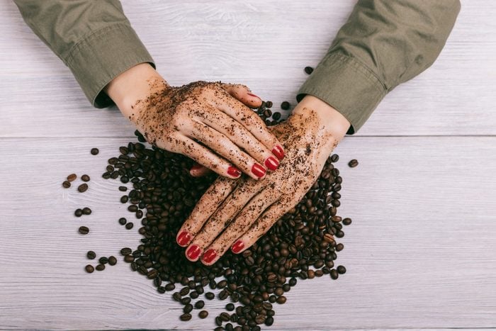 Women's hands with red nail polish applied the coffee scrub