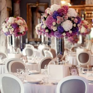 Round dinner table decorated with pink and violet hydrangeas stands in luxurious restaurant