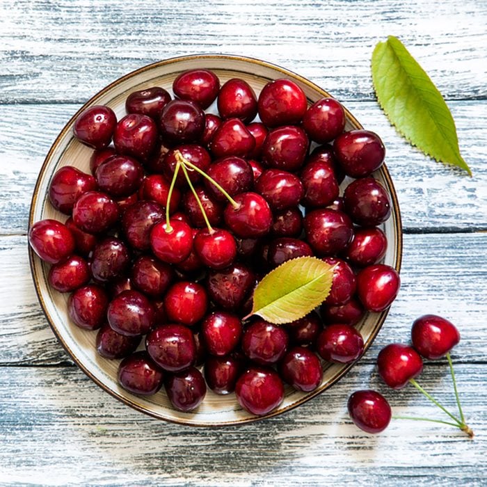 Fresh cherry on plate on wooden blue background. fresh ripe cherries. sweet cherries