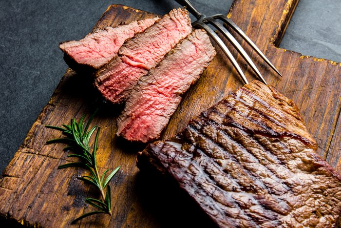 Sliced grilled medium rare beef steak served on wooden board