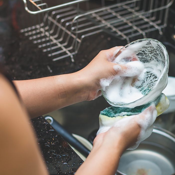A woman washing bowl glass by dish soap make many bubble