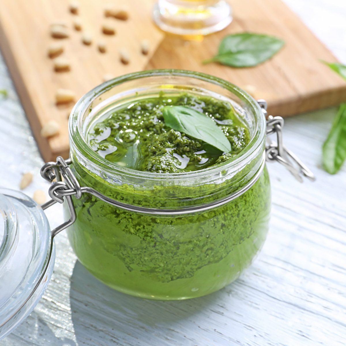 Jar with delicious basil pesto sauce on table