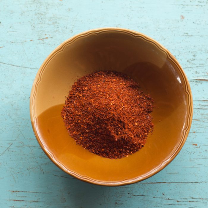Red cayenne pepper on ceramic bolw on blue pastel wooden table background
