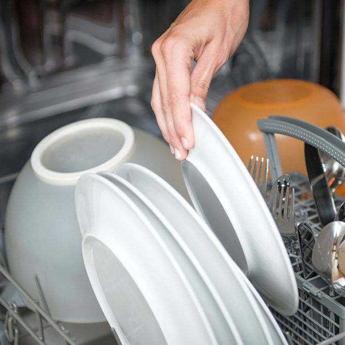 person loading plates in dishwasher
