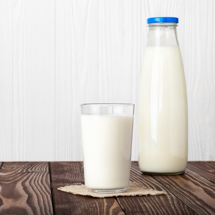 milk in glass and bottle with napkin on wooden table isolated on white background