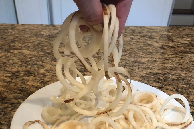 Person holding uncooked potato spirals