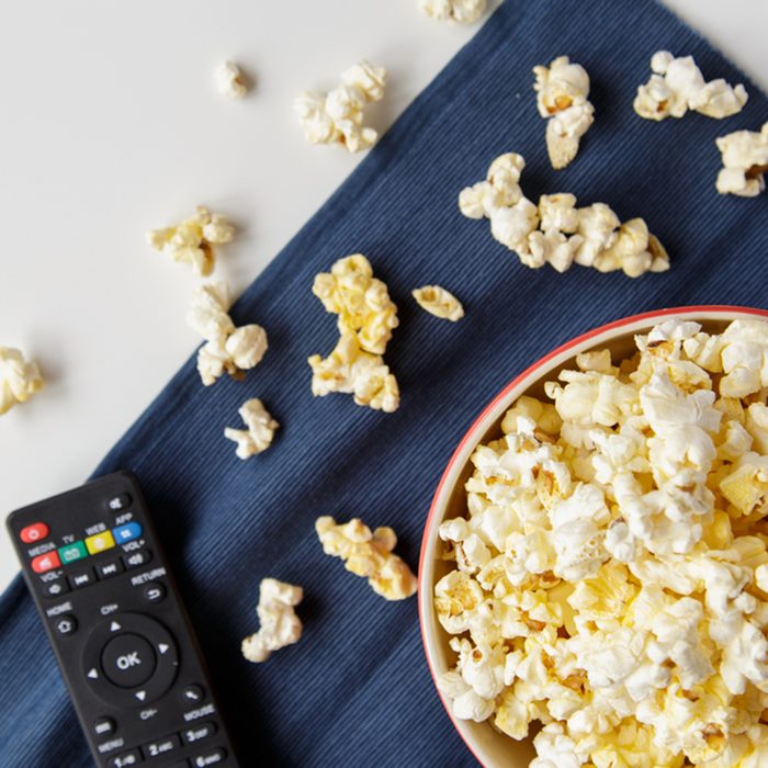 Popcorn with remote control on white table.