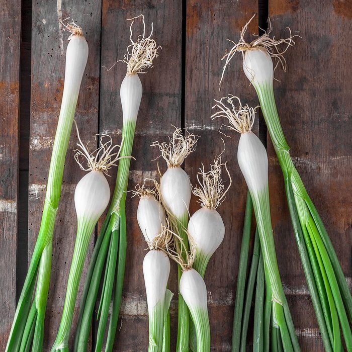 Green onions overhead group on old rustic wooden table in studio