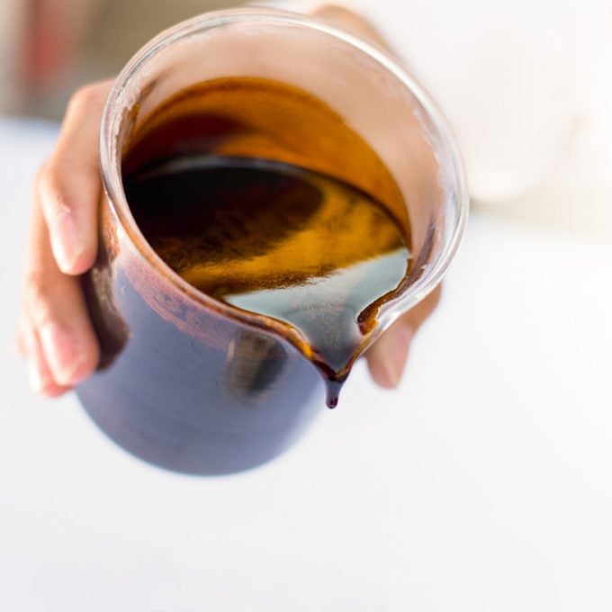 Dripping black treacle or molasses from beaker. Molasses is the final product from the sugarcane extraction process of sugar factory industrial. Background with copy and text space. - Selective focus.; Shutterstock ID 1005612643; Job (TFH, TOH, RD, BNB, CWM, CM): TOH