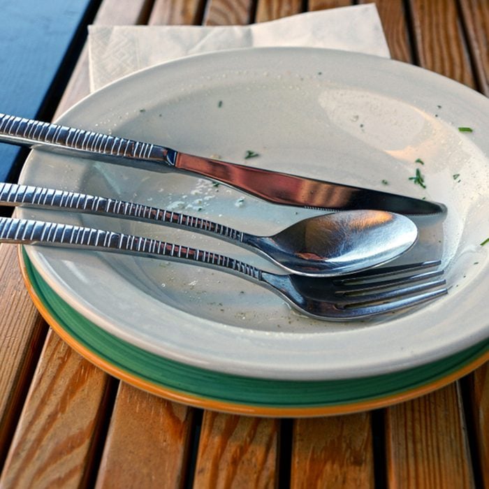 Dirty dishes with cutlery on a brown wooden table