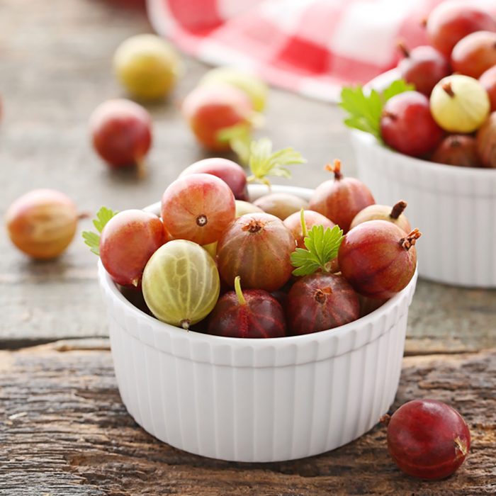Ripe gooseberries fruit in bowl on wooden table