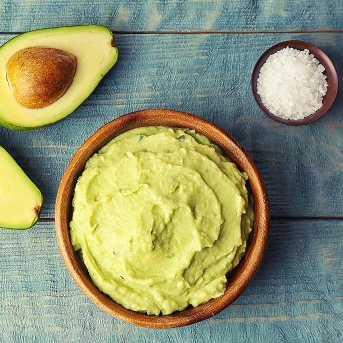 Flat lay composition with guacamole sauce, salt and ripe avocado on wooden background