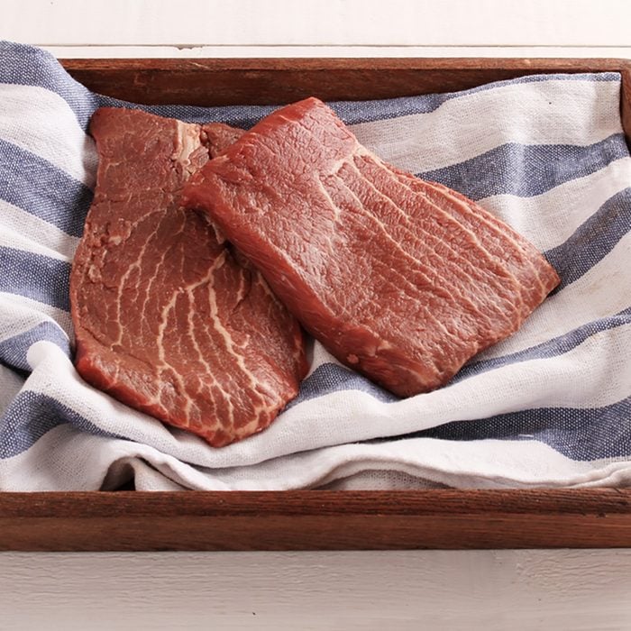fresh flat pan beef steak in wooden tray