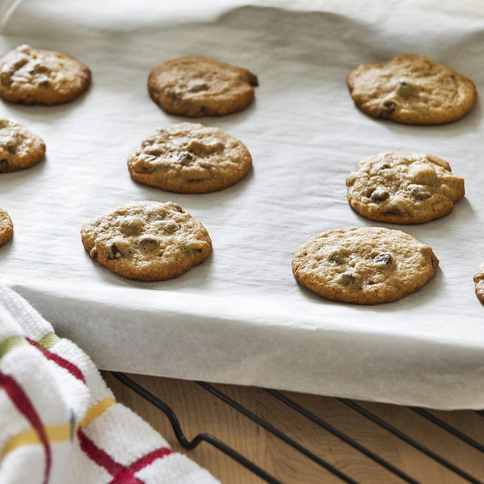 Hot freshly baked chocolate chip cookies are cooling on a parchment paper lined baking sheet.