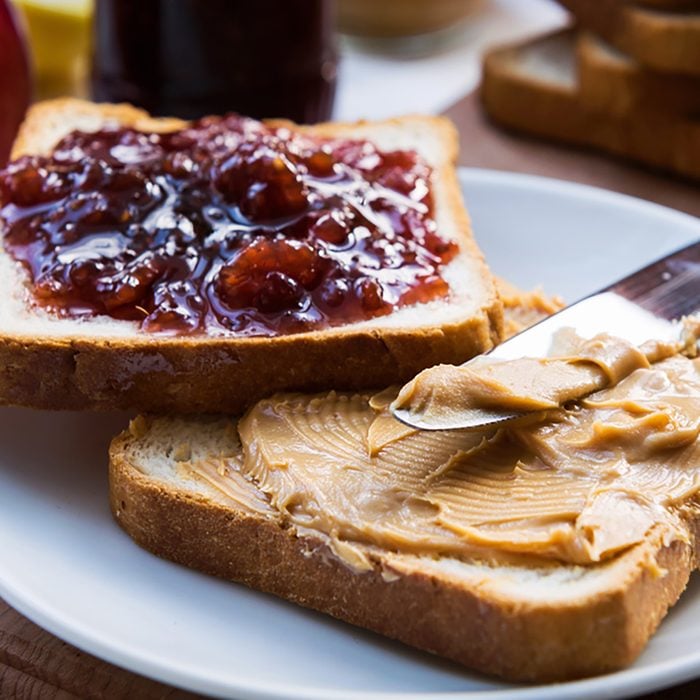 Peanut butter and raspberry jelly sandwich on wooden background. 