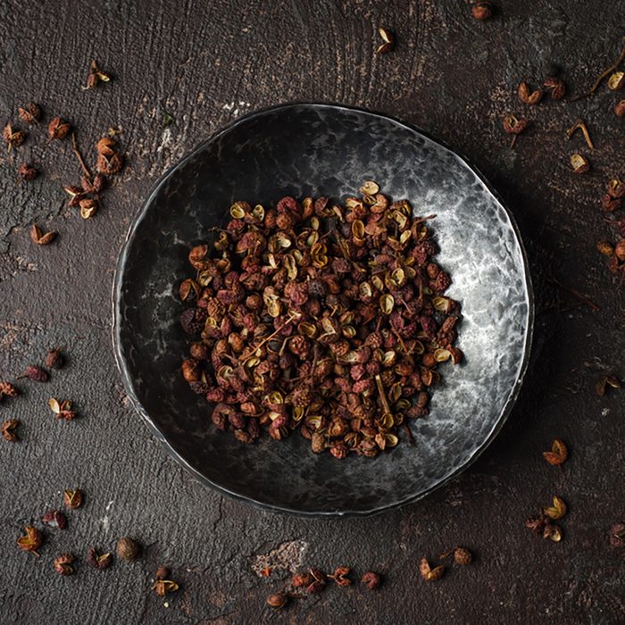 Szechuan peppercorns - Sichuan pepper in metal bowl on dark background. Selective focus