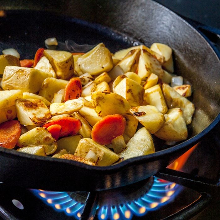 Potatoes in skillet over a fire.