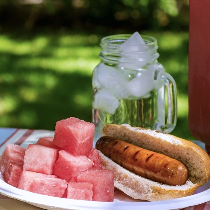 Picnic with Brats, Watermelon, and Ice Water in a Red Cooler in the Shade; Shutterstock ID 411394444
