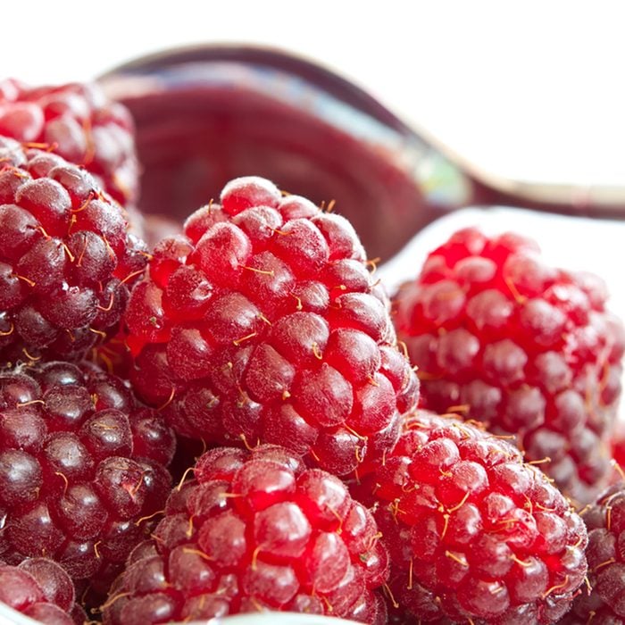 Loganberries on white background with a spoon