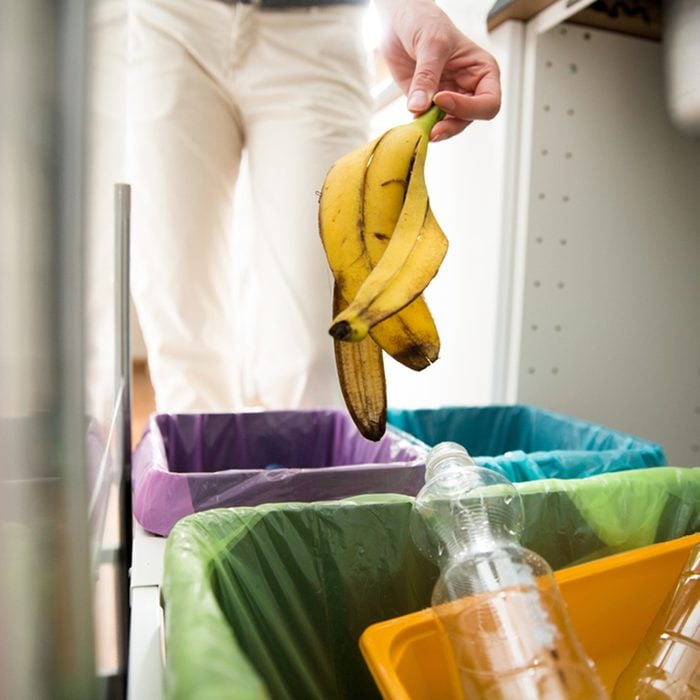 Woman putting banana peel in recycling bio bin in the kitchen.