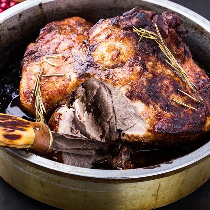 Whole oven roast pork shank with herbs and spicy marinade in roasting pan ready to eat 