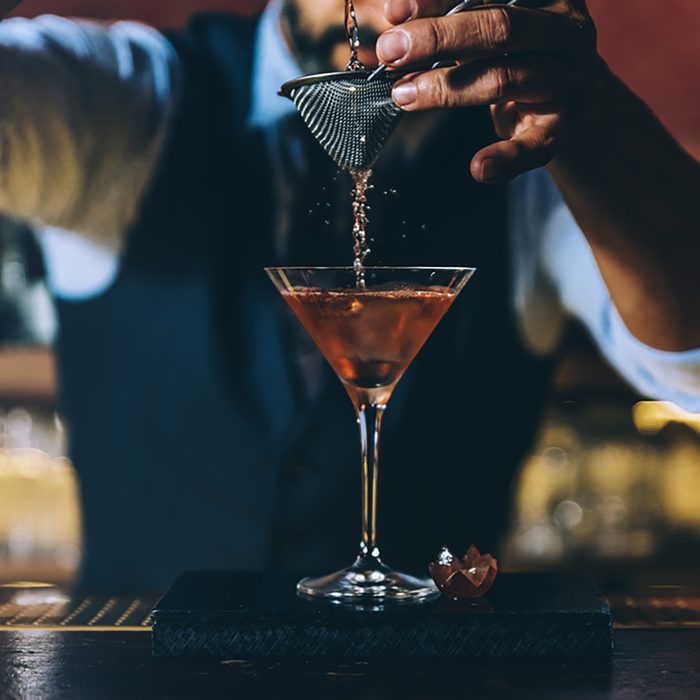 Expert barman is making cocktail at night club.
