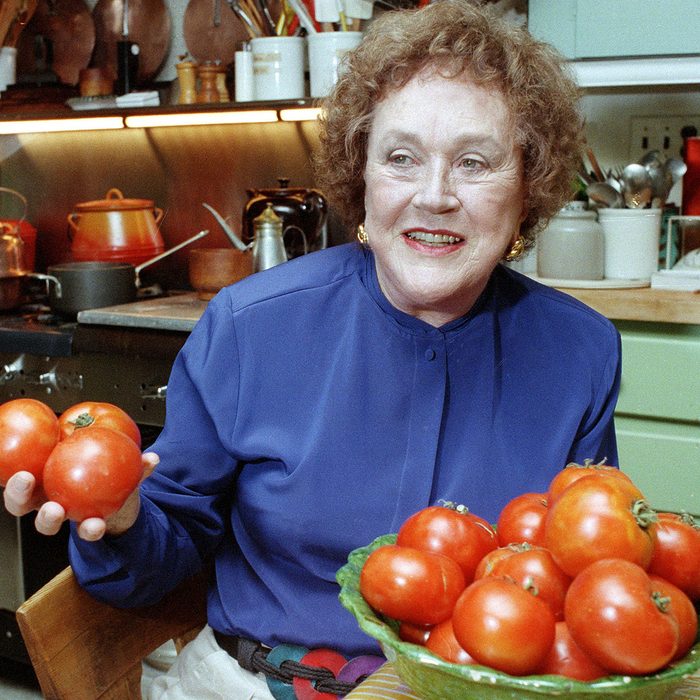 Julia Child holds tomatoes in the kitchen at her home