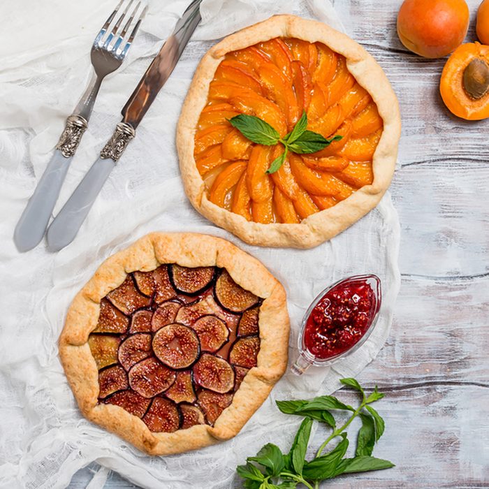 Homemade apricot and figs galette made with fresh organic apricotes and fig jam on wooden table.