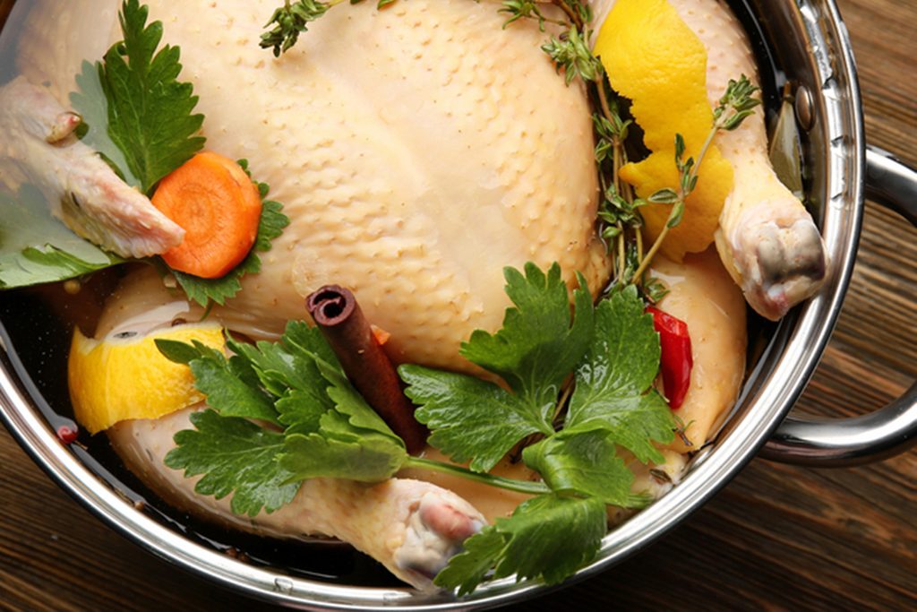 Cooking pot with turkey soaked in flavored brine on wooden table