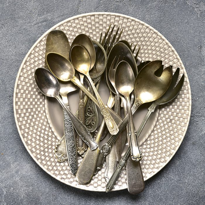 Vintage silverware on a plate over dark grey slate,stone or concrete background.
