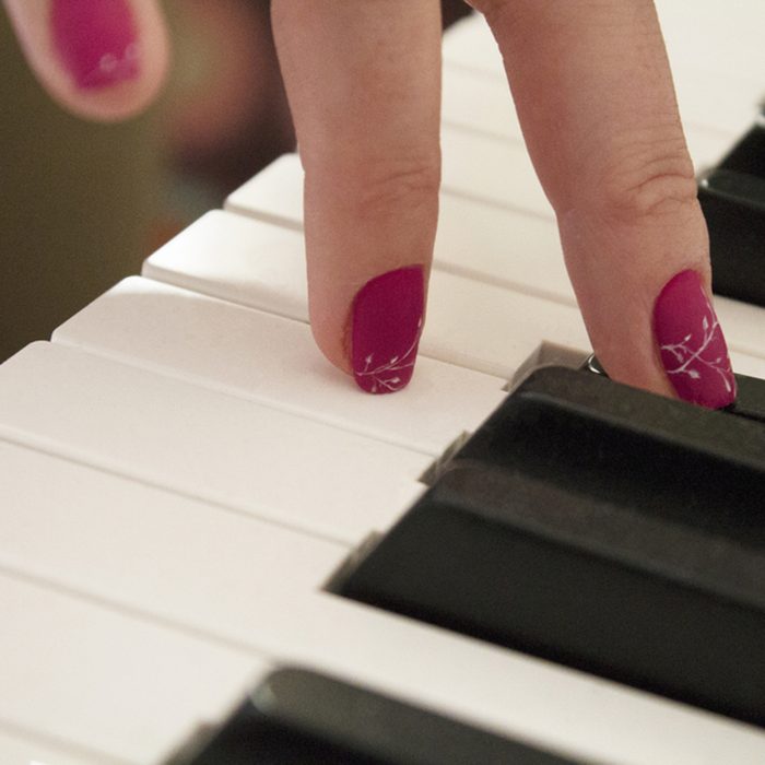 woman with beautiful manicure playing the piano