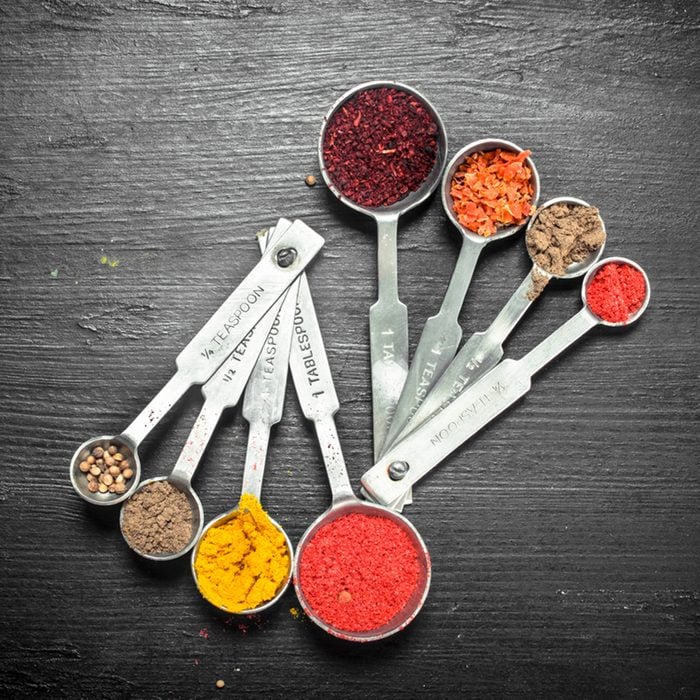 Ground spices in measuring spoons. On the black chalkboard.