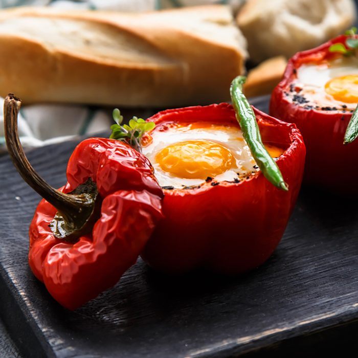 Baked red peppers stuffed with eggs and sausage with bread and green beans, close view