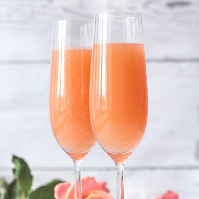 Two glasses of bellini cocktail with bouquet of roses