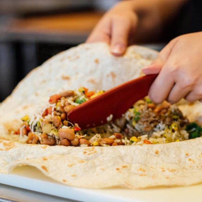 Person putting the fixing into a burrito