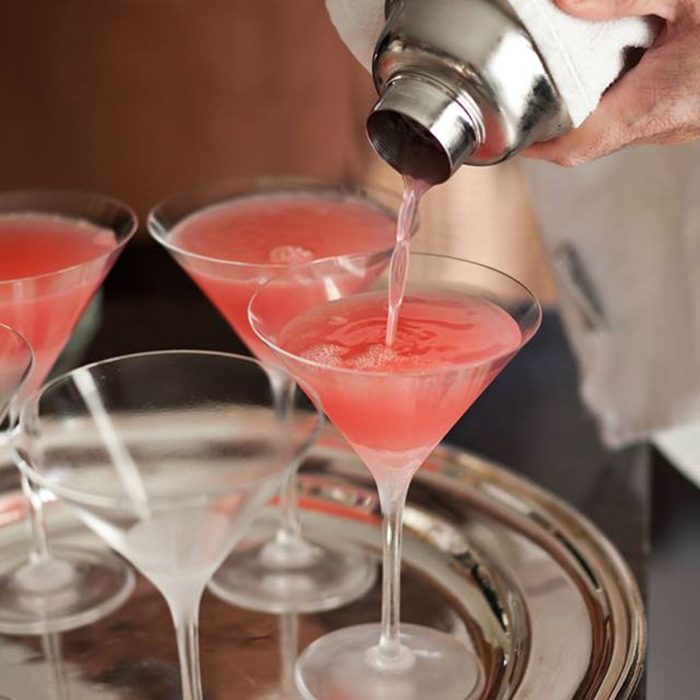 Person pouring drinks into cocktail glasses