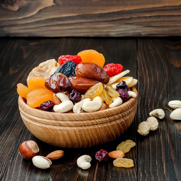 Mix of dried fruits and nuts on dark wood background